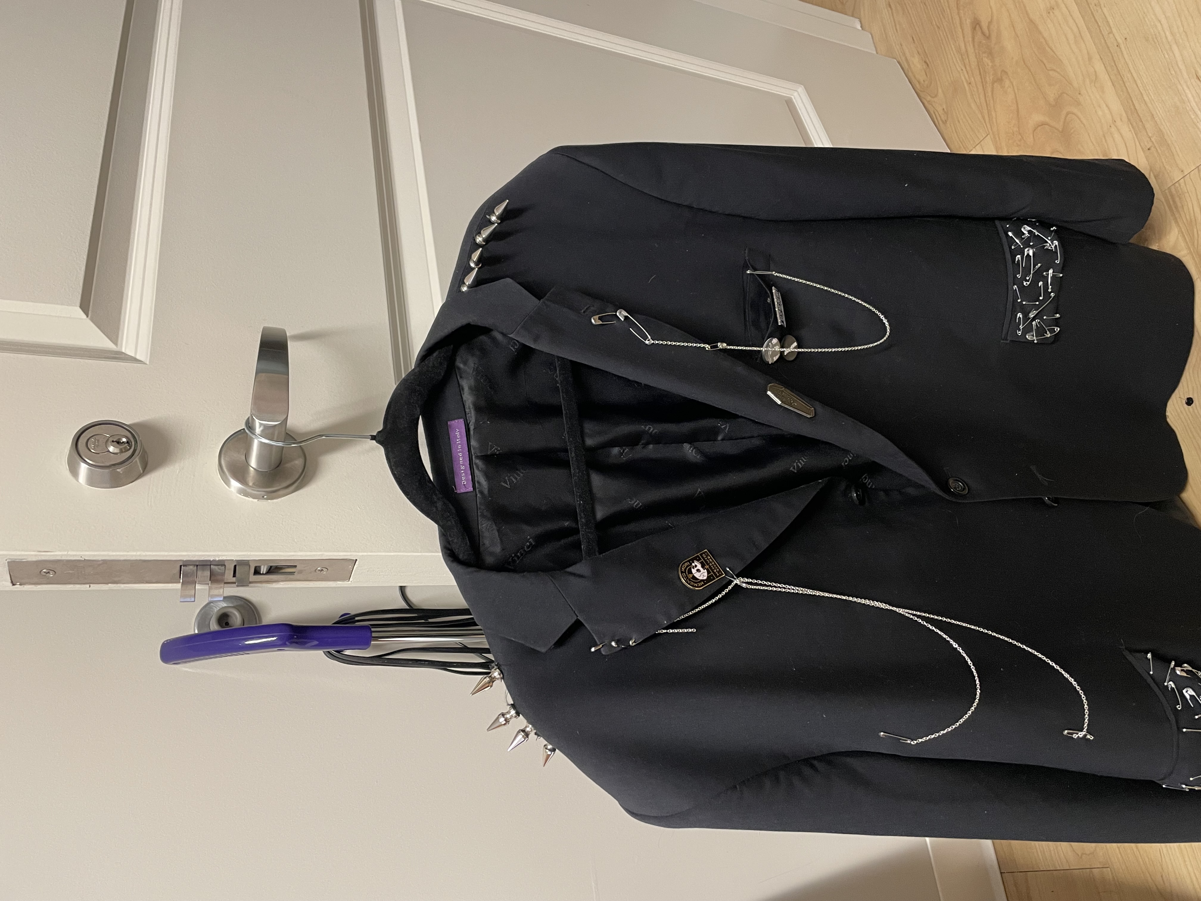 a black blazer with chains, spikes, saftey pins, and enamel pins.